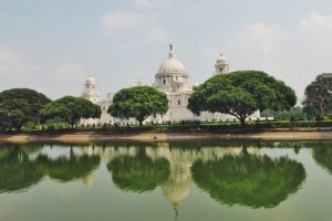 White tomb building near green tress and a lake